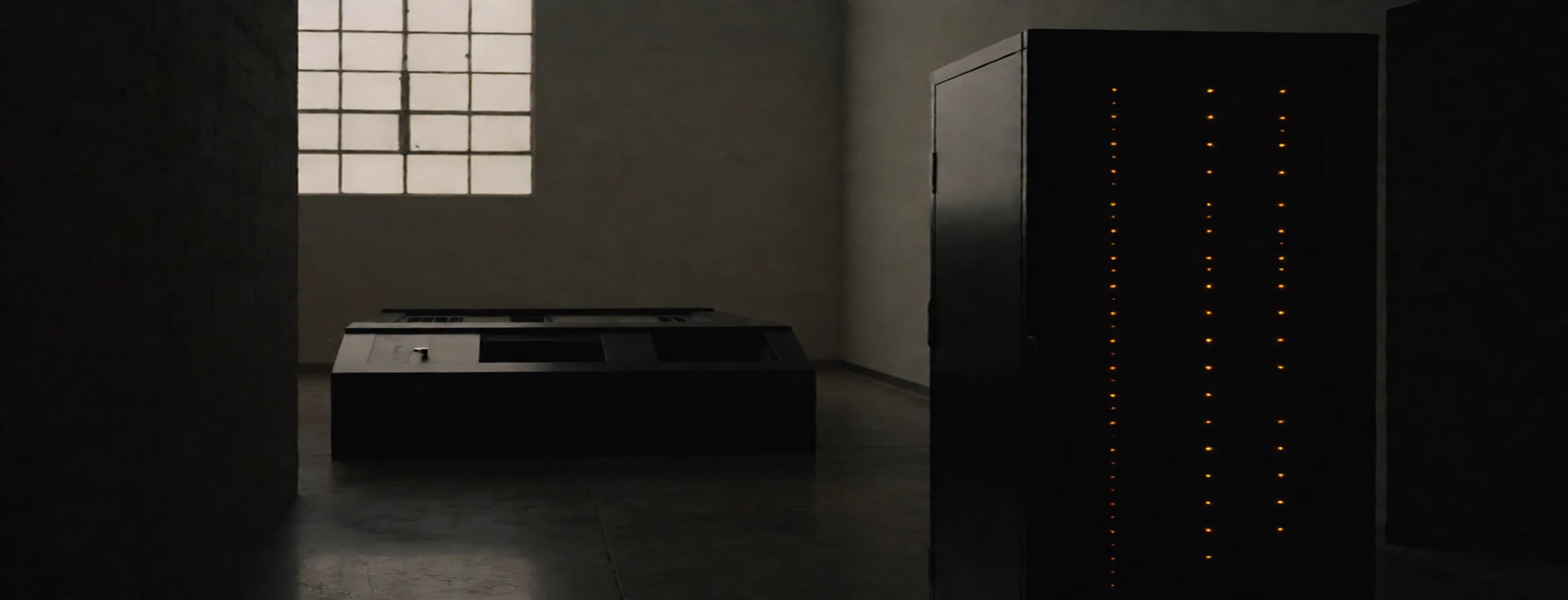 Modern hallway with black leather sofas on left and lit concrete wall on right leading to a glass door.