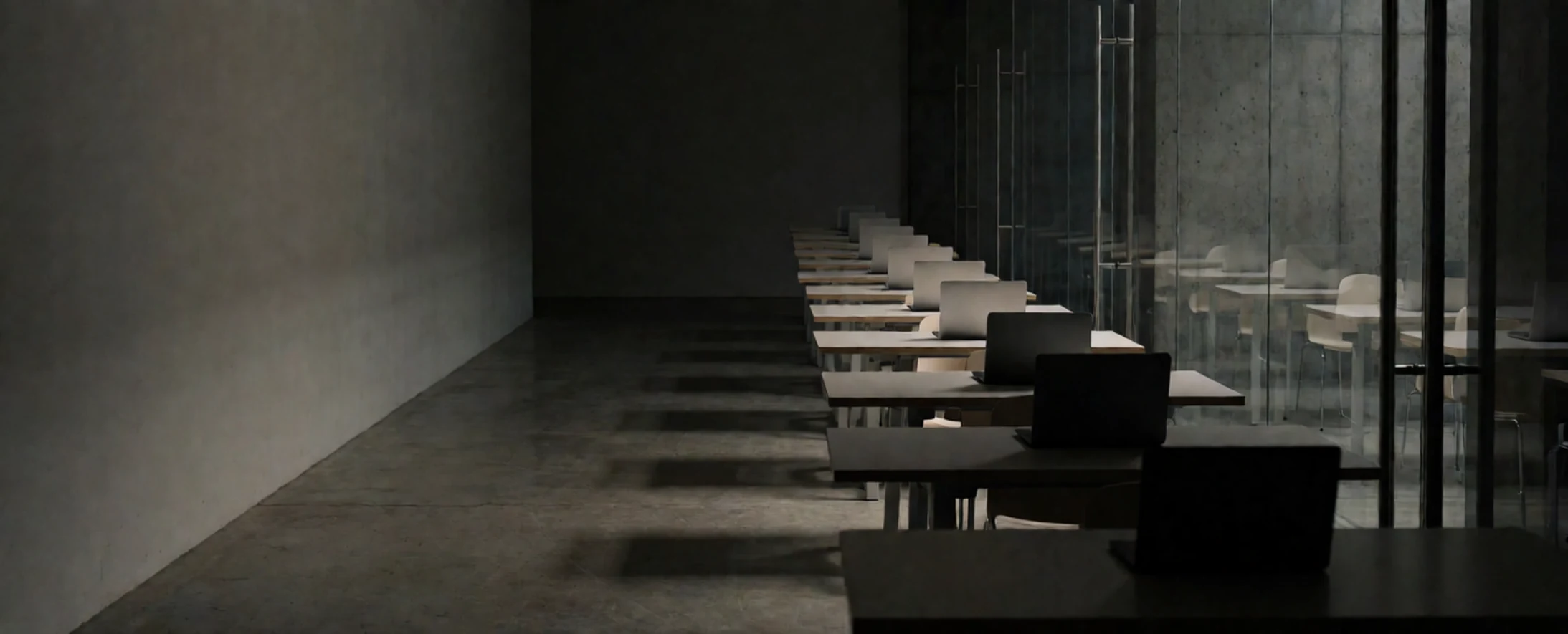 Dark modern gym with treadmills, a yoga mat, dumbbells, and exercise balls near a glass wall.